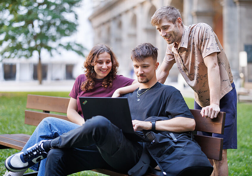 Foto von Studierenden, die gemeinsam in einen Laptop blicken